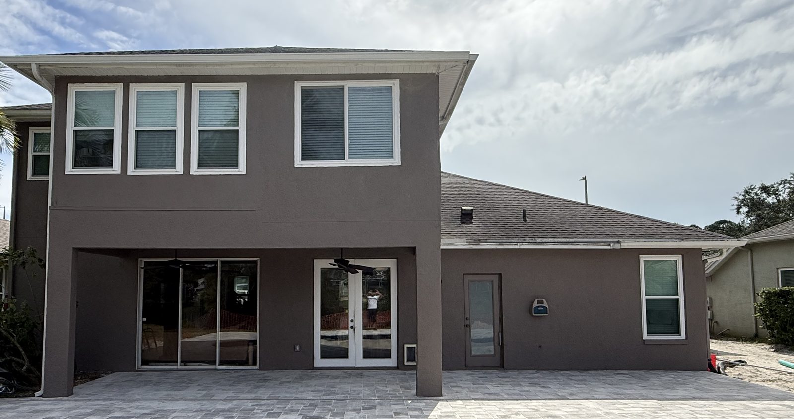 Exterior repaint in Westchase, Tampa — rear elevation of a two-story stucco home after cleaning, re-caulking, primer and two finish coats